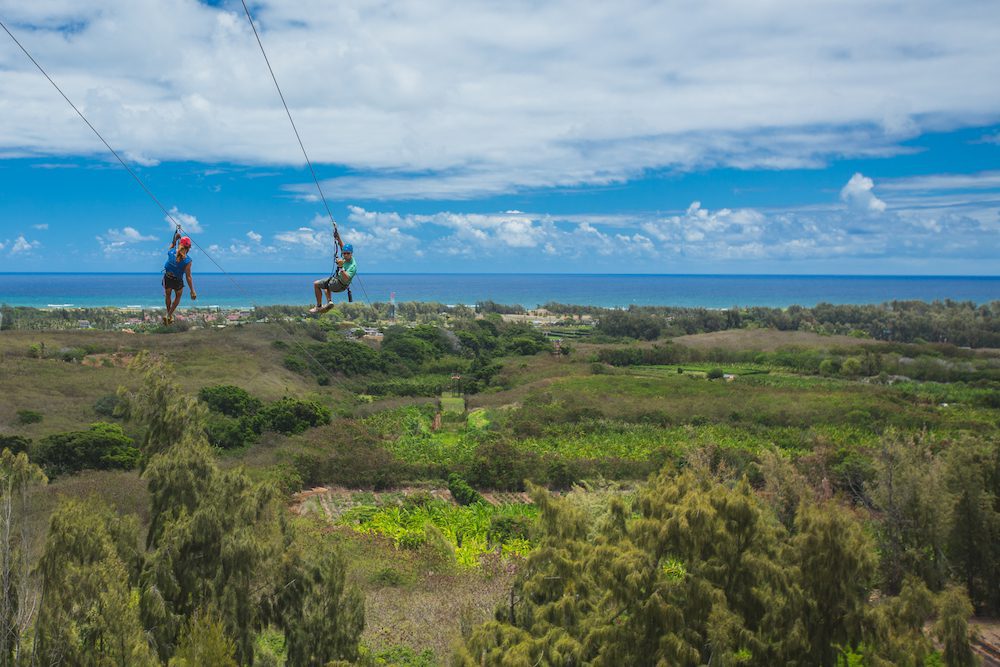 Two people ziplining in Oahu at CLIMB Works Keana Farms.