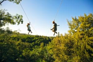 A couple riding one of our ziplines in Oahu.