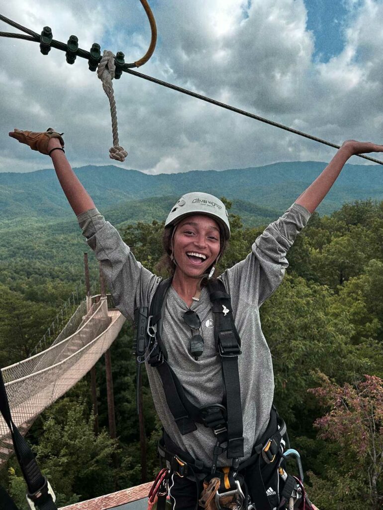 A zipline guide celebrates with a smile as before she sends visitors on zipline