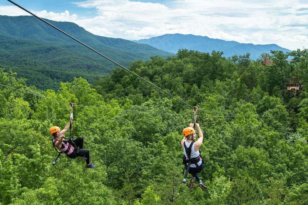 two woman enjoy dual ziplines as they race toward a platform in the Smoky Mountains
